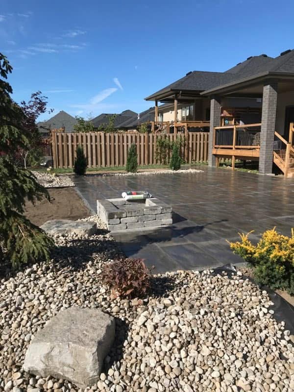 Backyard patio installation with river rock and new plantings